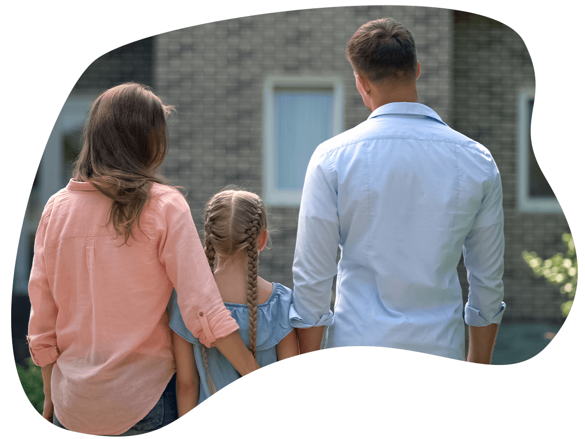 A couple and their daughter standing in front of their home