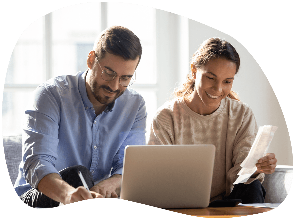 A couple smiling while using a laptop and reviewing documents