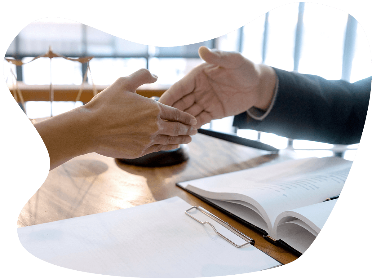 Closeup of two people about to shake hands over a desk full of paperwork