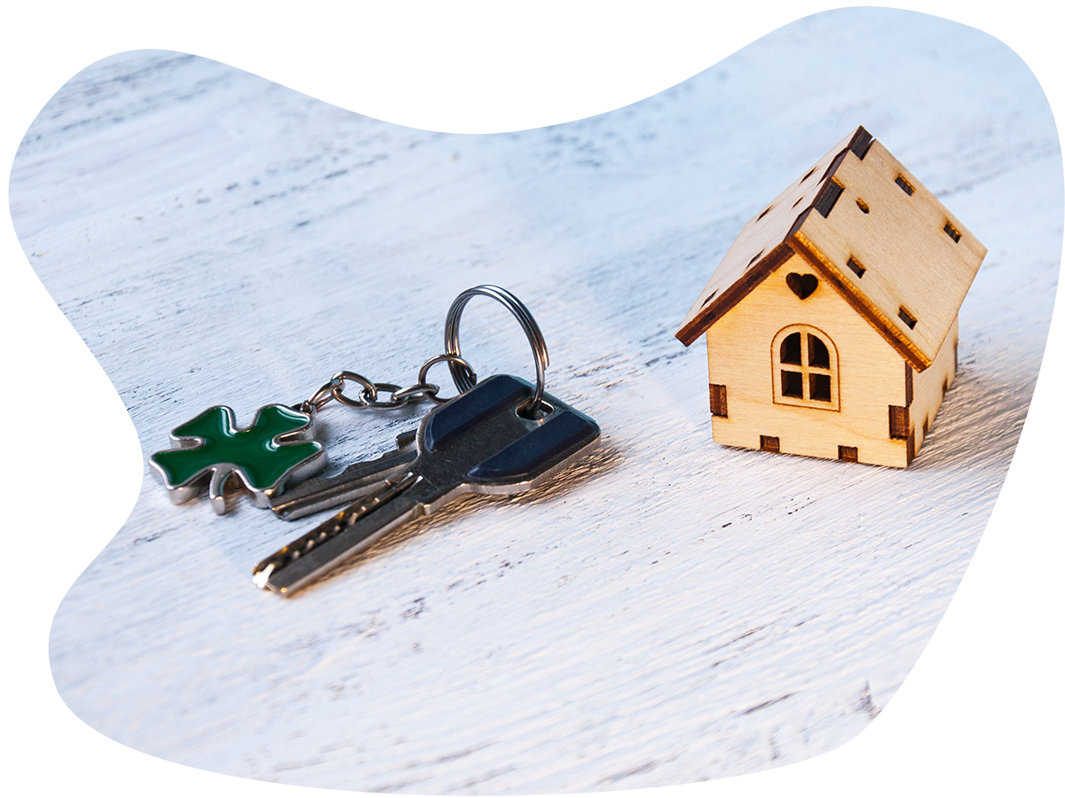 Small wood home model sits next to a set of housekeys